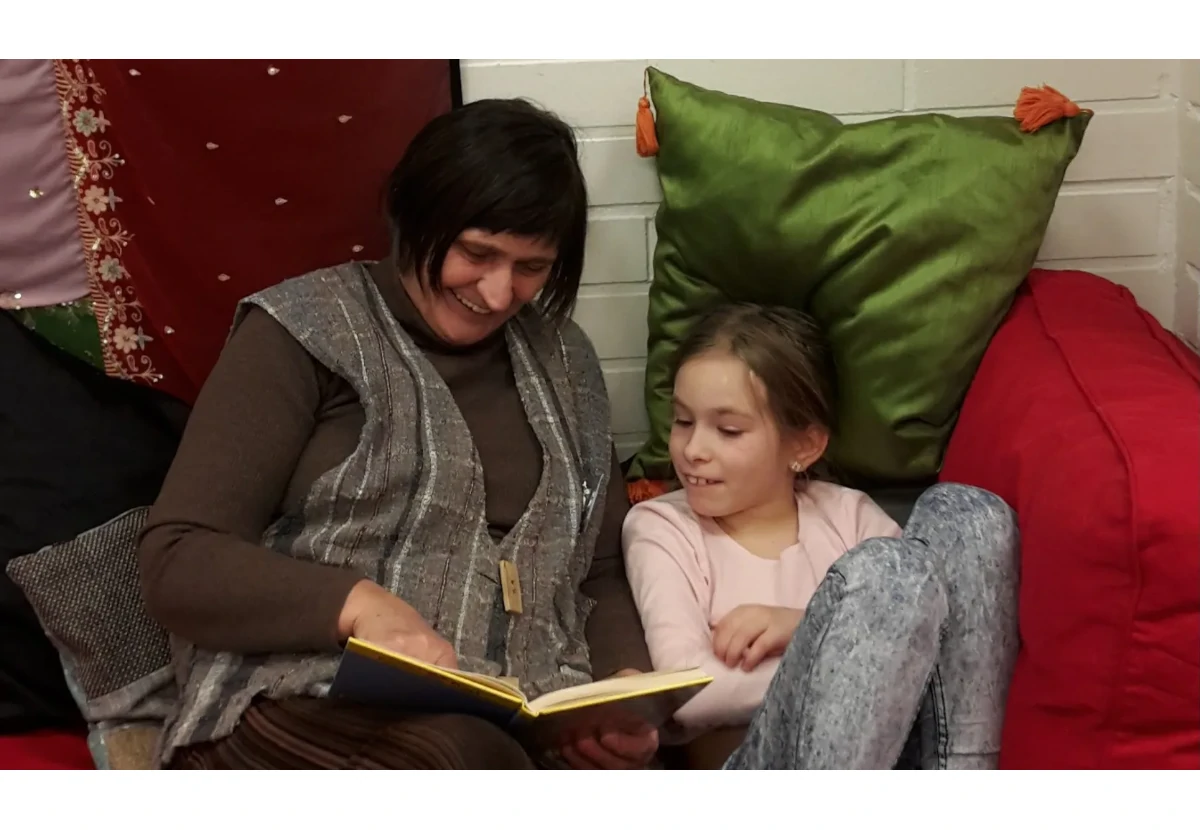 tyttö ja mummi lukevat kirjaa yhdessä