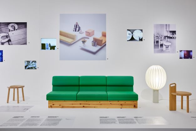 Taiteellinen kuva jossa vihreä sohva ja tauluja huonekaluista seinällä.