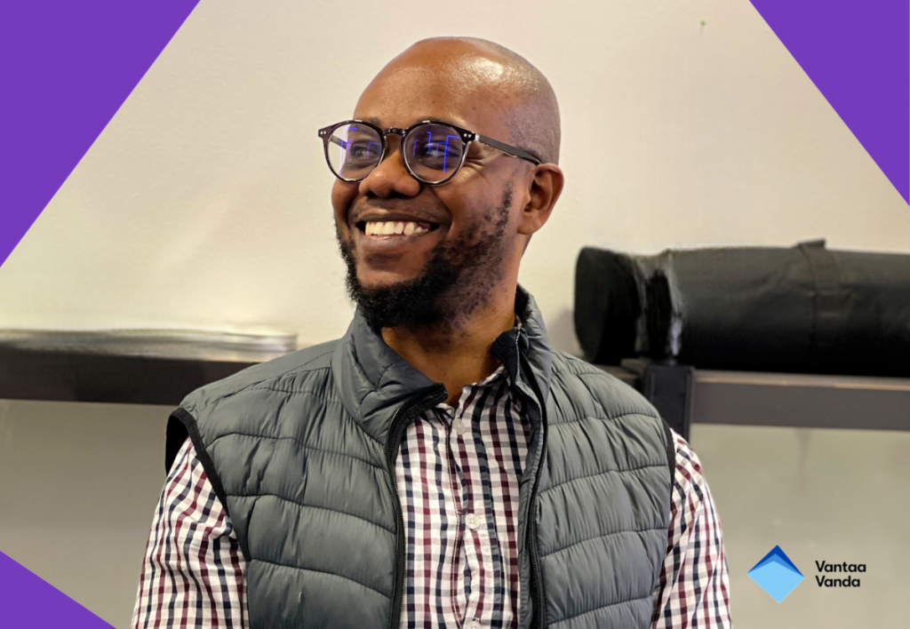 Tummaihoinen mies silmälasit päässään. Hänellä on lyhyt parta ja yllään kauluspaita ja tikkiliivi.