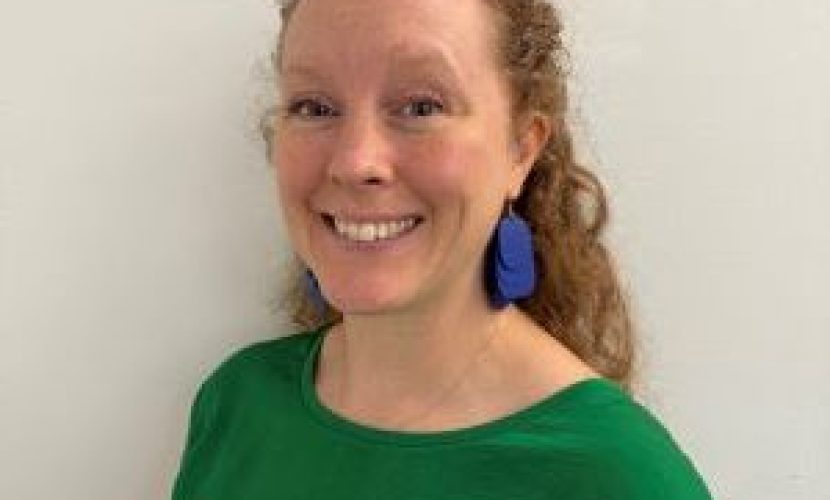 Magdalena hymyilee kameralle profiilikuvassa. Hänellä on kiharat punertavat hiukset, pisamia, siniset korvakorut ja kirkkaanvihreä paita.